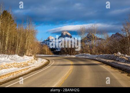 Eine kurvenreiche gepflasterte Straße zum Skigebiet Grand Targhee blickt auf den Gipfel des Grand Teton in Wyoming. Stockfoto