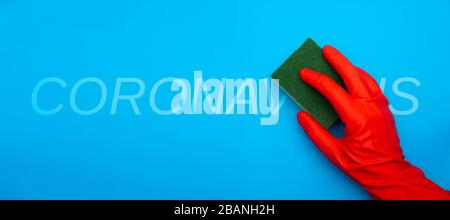 Konzeptbild der Hand aus rotem Gummi schützender Handschuhhalterschwamm mit grünem Faserreinigungskoronavirus Text isoliert auf klassischem blauem Hintergrund Stockfoto