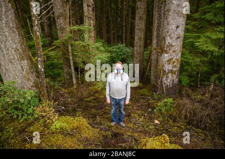 Mann, der während des Coronavirus-Ausbruchs MITTEN im Wald eine Gasmaske trägt; kein Entkommen Stockfoto