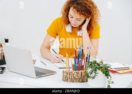 Eine Künstlerin, die an einem Tisch sitzt, zieht Blätter in Bleistift Stockfoto