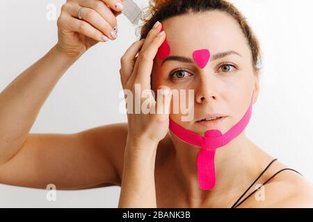 Frau, sie klebt ihr ein kinesiologisches Band ins Gesicht Stockfoto