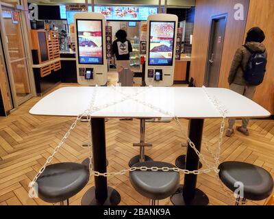 Montreal, Kanada - 22. März 2020: Verkettete Sitze und Tische in McDonalds aufgrund von Coronavirus. Viele Restaurants und Fastfood-Plätze legen Kette auf Tische Stockfoto