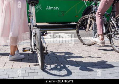 Frau steht in der Nähe von Fahrrad- und Mannbeinen auf dem Fahrrad vor der Querstraße Stockfoto