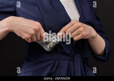 Mädchen in einer Jacke entfernt US-Dollar auf schwarzem Hintergrund. Nahaufnahme. Stockfoto