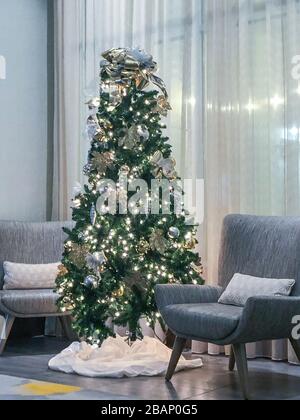 Innenaufnahme eines Weihnachtsbaums, umgeben von modernen Stühlen in einem Business Lobby-Bereich Stockfoto