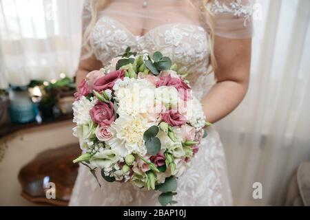 Die Frau in einem schönen Hochzeitskleid und ihrem brautstrauß mit Blumen Stockfoto