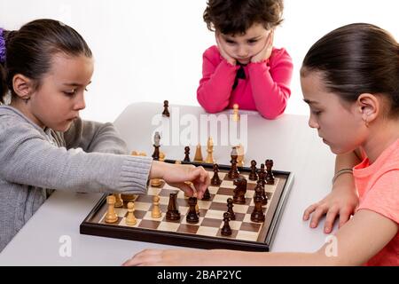 Schwestern, die gemeinsam Schach spielen, isoliert auf Weiß. Konzept für die Konzentration von Kindern. Stockfoto