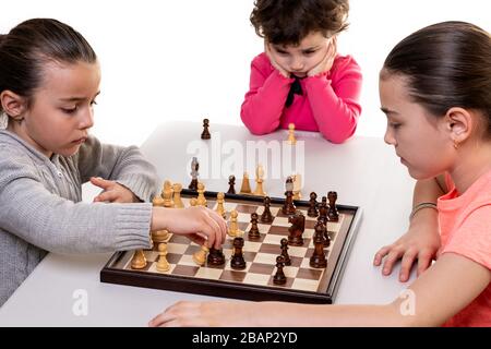 Schwestern, die gemeinsam Schach spielen, isoliert auf Weiß. Konzept für die Konzentration von Kindern. Stockfoto