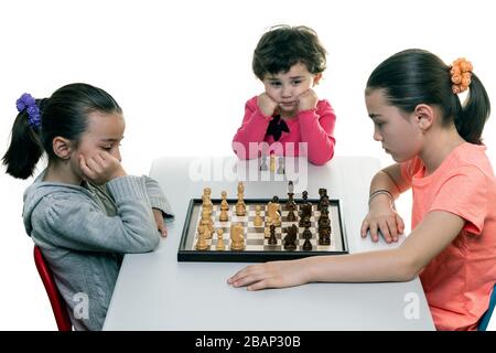 Schwestern, die gemeinsam Schach spielen, isoliert auf Weiß. Konzept für die Konzentration von Kindern. Stockfoto