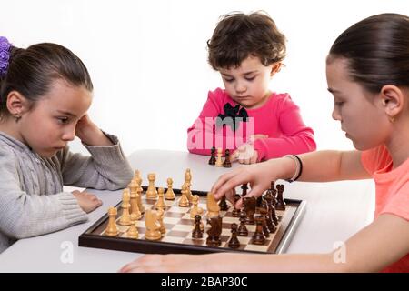 Schwestern, die gemeinsam Schach spielen, isoliert auf Weiß. Konzept für die Konzentration von Kindern. Stockfoto