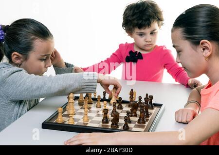 Schwestern, die gemeinsam Schach spielen, isoliert auf Weiß. Konzept für die Konzentration von Kindern. Stockfoto