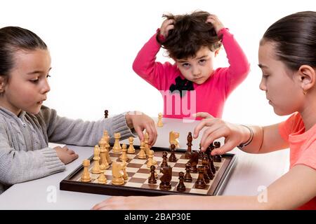 Schwestern, die gemeinsam Schach spielen, isoliert auf Weiß. Konzept für die Konzentration von Kindern. Stockfoto