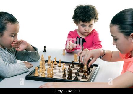 Schwestern, die gemeinsam Schach spielen, isoliert auf Weiß. Konzept für die Konzentration von Kindern. Stockfoto