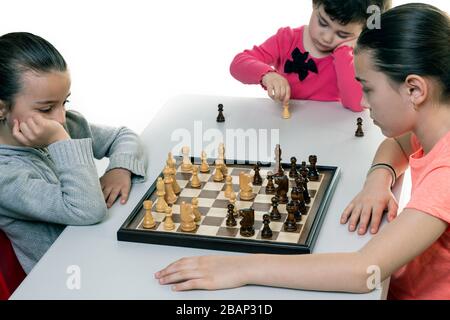 Schwestern, die gemeinsam Schach spielen, isoliert auf Weiß. Konzept für die Konzentration von Kindern. Stockfoto