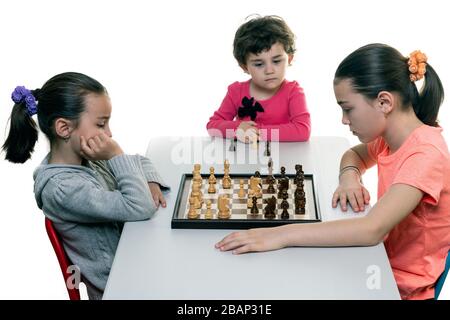 Schwestern, die gemeinsam Schach spielen, isoliert auf Weiß. Konzept für die Konzentration von Kindern. Stockfoto