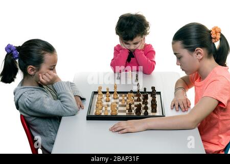 Schwestern, die gemeinsam Schach spielen, isoliert auf Weiß. Konzept für die Konzentration von Kindern. Stockfoto