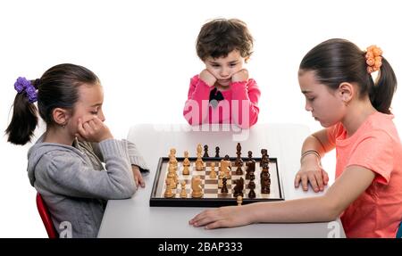 Schwestern, die gemeinsam Schach spielen, isoliert auf Weiß. Konzept für die Konzentration von Kindern. Stockfoto