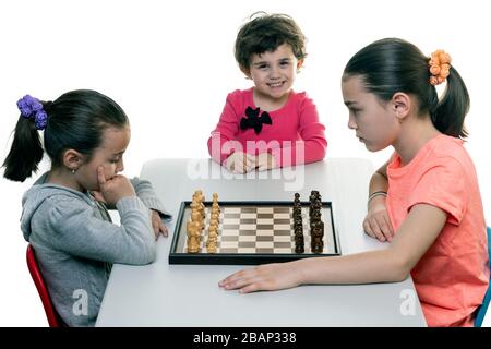 Schwestern, die gemeinsam Schach spielen, isoliert auf Weiß. Konzept für die Konzentration von Kindern. Stockfoto