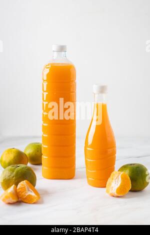 Das ist das Bild von Orangensaft in einer Flasche auf Marmor mit Orangen. Stockfoto