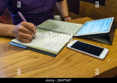Man-Handschrift auf dem Notebook neben Handy und Tablet Stockfoto