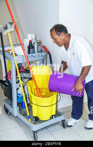 Miami Beach, Florida, Presidential Condominiums, Depotarbeit, Angestellter, hispanischer Mann, männlicher Hausmeister in einen Moppeimer, der Wasser Handarbeit gießt Stockfoto