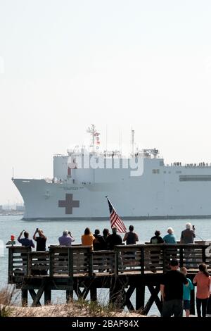 Norfolk, USA. März 2020. Die Menschen versammeln sich, um zu sehen, wie das Militär-Sealift-Kommando-Lazarettschiff USNS Comfort (T-AH 20) von der Naval Station Norfolk, Virginia, am 28. März 2020 abfährt. Trost unterstützt die nationÕs COVID-19-Reaktionsmaßnahmen und dient als Überweisungskrankenhaus für Patienten, die derzeit nicht an Land stationierten COVID-19-Patienten sind. So können Krankenhäuser in Landhäusern ihre Bemühungen auf COVID-19-Fälle konzentrieren. Eine der Missionen des Ministeriums für DefenseÕs ist die Verteidigungsunterstützung der Zivilbehörden. Kredit: Storms Media Group/Alamy Live News Stockfoto