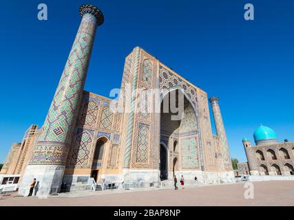 Ulugh Beg Madrasah (islamische Schule) und seine zwei Minarette. Blau/türkisfarbene Kuppel von Tilya Kori Madrasa sichtbar in der Registan, Samarkand, Usbekistan. Stockfoto