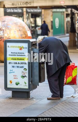 Zagreb, Kroatien - 19. März 2020: EIN älterer Mann sucht Plastikflaschen in einem Mülleimer, damit er sie auf der Straße gegen Geld austauschen kann Stockfoto