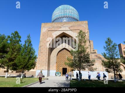 Blick auf den Innenhof des Seitengebäudes der Bibi-Khanym-Moschee. Perser mit blauen Keramikfliesen und türkisfarbener Kuppel. Bibi Khanum in Samarkand, Usbekistan. Stockfoto