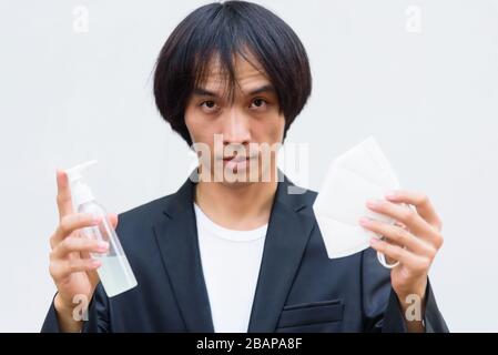 Ein asiatischer Mann zeigt N95-Maske und Alkoholgel zum Schutz vor krankhaften Koviden 19 Stockfoto