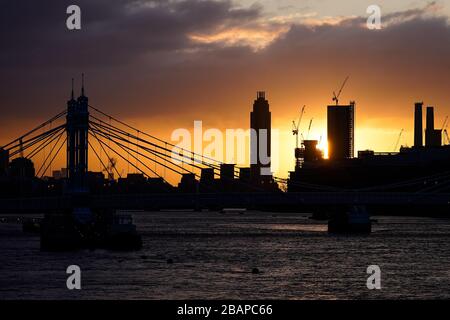 Die Sonne steigt hinter den in London im Bau befindlichen Turmblocks auf, während sich die Uhren eine Stunde vor der britischen Sommerzeit (BST) bewegen. Stockfoto