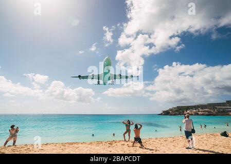 Ein Airbus A340 nähert sich über Touristen, Kameras bereit, am Maho Beach, St. Maarten Stockfoto