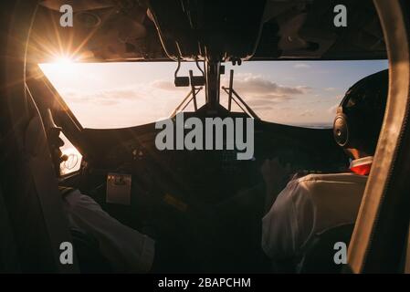 Die untergehende Sonne durchdringt das Cockpit-Fenster an Bord eines Winair DHC6 Twin Otter, auf einem Inselhüpfflug Stockfoto