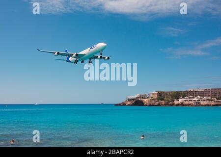 Ein Air France JOON Airbus A340-300 fährt über Touristen am Maho Beach, St. Maarten Stockfoto