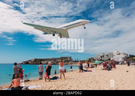 Ein Gulfstream Privatjet fliegt über Touristen am Maho Beach, St. Maarten Stockfoto