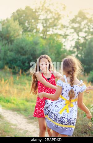 Zwei fröhliche kleine Mädchen, die Spaß haben und am sonnigen Sommertag im Freien tanzen Stockfoto