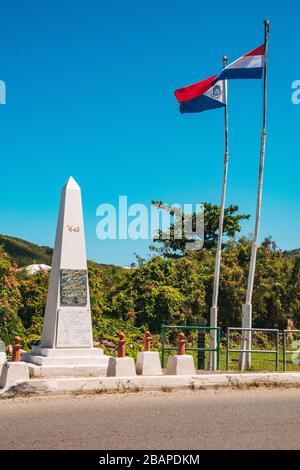 Flaggen fliegen am Denkmal der Einheit und Freundschaft an der Grenze zwischen der französischen und niederländischen Seite der Karibikinsel St. Martin / St. Maarten Stockfoto