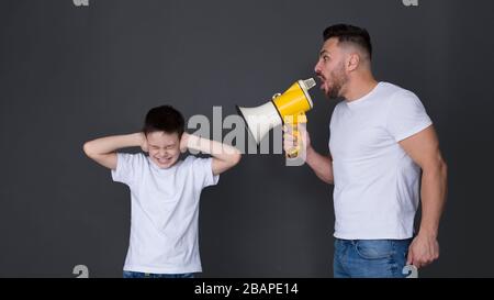 Nervöser Vater schreit mit Megafon auf Sohn Stockfoto