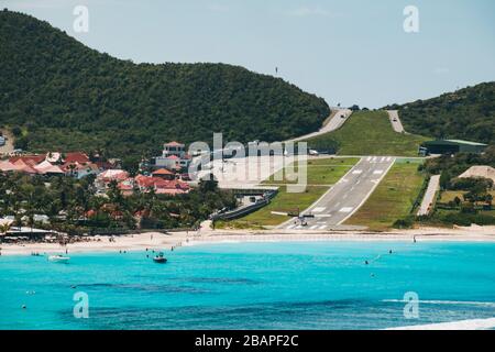 Ein Flugzeug fliegt am Flughafen Saint Barthélemy, Französisch Karibik, eine Landebahn 28 über dem Strand an Stockfoto