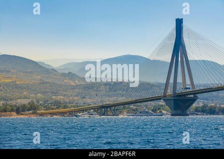 Griechenland. Brücke über den Golf von Korinth an einem sonnigen Sommertag. Moderne Motoryacht und Fähre Stockfoto