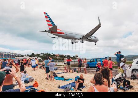 Eine Boeing 767-300er von American Airlines pfeift über einen Maho Beach, der mit Touristen von einem Kreuzfahrtschiff überfüllt ist, während sie bei Sint Maarten landet Stockfoto