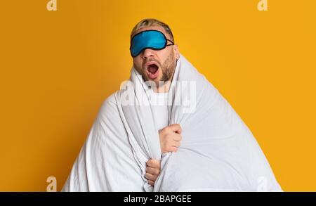 Kerl in Maske für Schlaf-Yawns in Decke Stockfoto