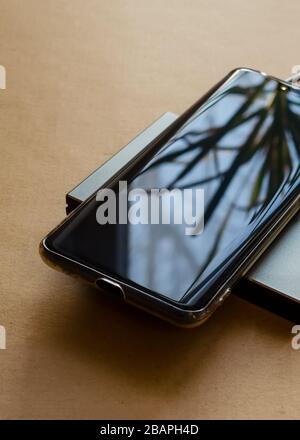 Das Telefon wird über ein rechteckiges Induktionsladegerät aufgeladen. Kabelloses Ladegerät Stockfoto