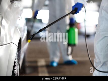 Unerkennbare Arbeiter, die Auto mit Chemikalien waschen, Kovid 19 Stockfoto