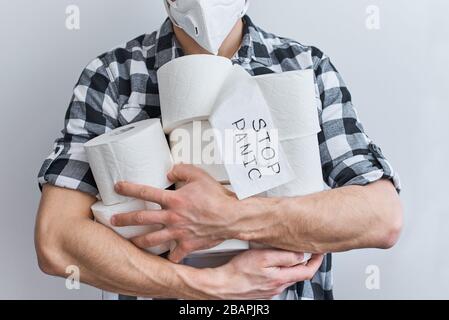Hör auf, Panik wegen Coronavirus wegen Hausquarantäne zu kaufen. Bleiben Sie zu Hause, um ein Konzept für den Schutz vor Kovid 19 zu erhalten. Mann in Schutzmaske hält Gewebe-wc-Papier Stockfoto