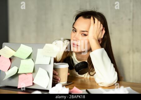 Überarbeitete Frau, die vor dem Laptop sitzt Stockfoto