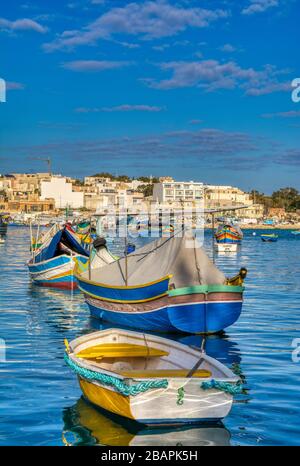 Marsaxlokk, Malta - 10. Januar 2020: Schöner Blick auf die traditionellen bunten Boote Luzzu im Hafen des Mittelmeer-Fischerdorfes Mars Stockfoto