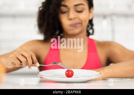 Afro Frau, die winzige Tomaten auf einem Teller betrachtet Stockfoto