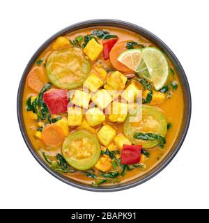 Ein gelber Veg Thai Curry mit Tofu und Gemüse isoliert auf weißem Hintergrund. Vegetarisches Thai-Curry mit Tofu, Zucchini, Paprika, Spinat, Karotte Stockfoto