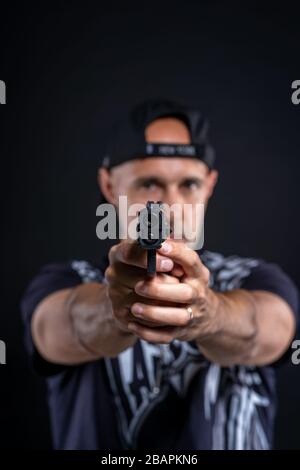 Mann zeigt Waffe auf Objekt, Porträt auf schwarzem Hintergrund Stockfoto